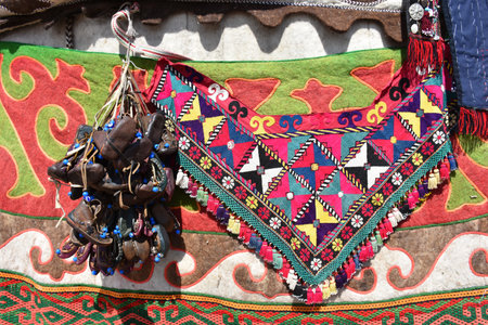 Traditional Asian children's shoes in leather hung on a wall and a traditional Turkish patterned...