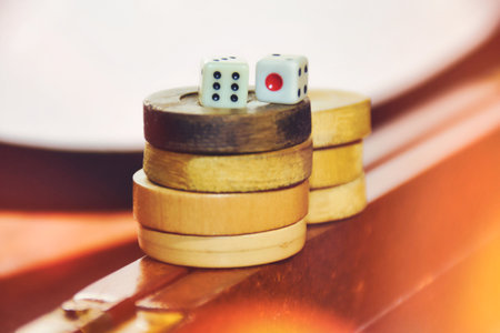 Wooden backgammon pieces stacked on top of each other on the backgammon board with game dice on themの写真素材