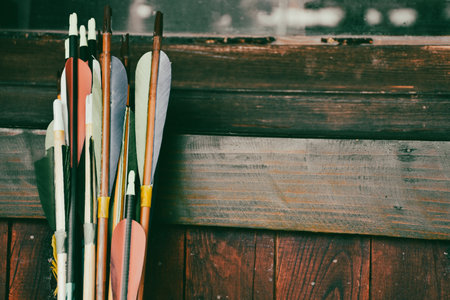 Colorful traditional archery arrows leaning vertically on colorful wooden panel. Ethnic sport backgroundの写真素材