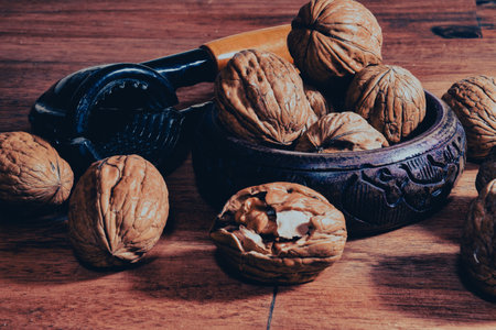 piles of walnuts waiting to be cracked in a wooden bowl on a wooden table. A walnut is cracked and its inside is visible. Organic healthy eatingの写真素材