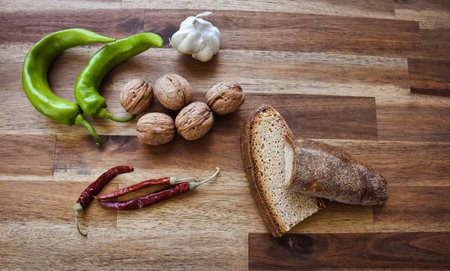 Roasted red peppers in an earthenware pot on a wooden table, accompanied by two slices of...