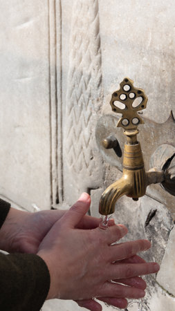 A woman washing her hands at a historical Ottoman fountain. Istanbul Turkeyの写真素材