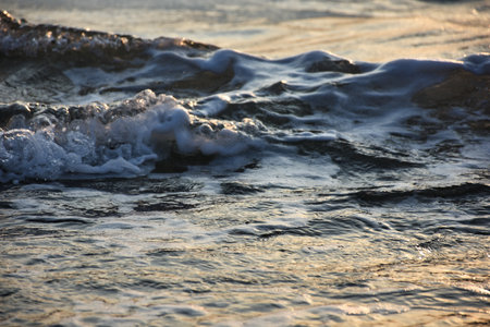 Sea waves on the beach in the evening at sunset. Close-up.
