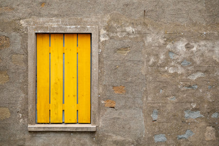 Yellow wooden window on the wall of an old house in Italy.の写真素材