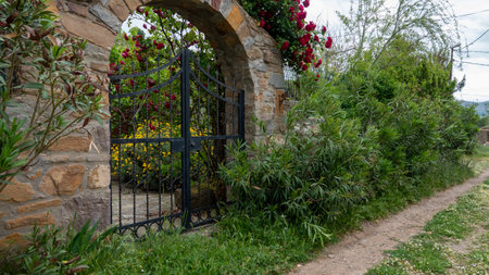 The entrance to the garden with a forged fence and flowers in the foreground