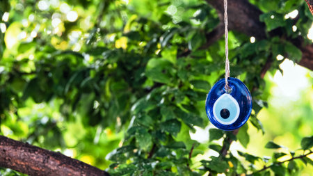 Blue evil eye bead hanging with a rope from a tree branch. Traditional Evil Eye Amulet. A national symbol and guardian in Turkey.. Selective focus.の写真素材