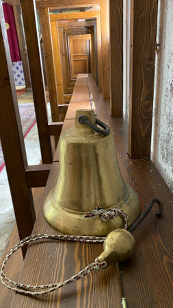 Old brass bell with a chain on a wooden table in the temple