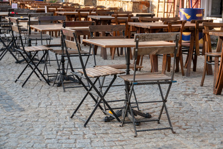 wooden folding iron chairs and tables placed on the street in front of an outdoor cafeの写真素材