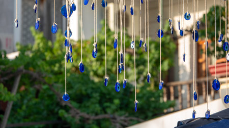 Blue evil eye beads hanging with a rope from a tree branch. Traditional Evil Eye Amulet. A national symbol and guardian in Turkey. The background is blurred.の写真素材