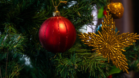 Christmas tree decorated with red ball and gold tinsel star and apple. close-up view. celebrating...
