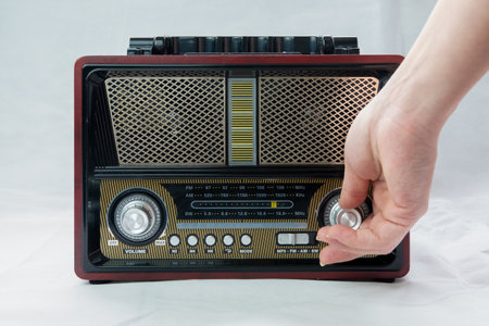A Female Fingers Tuning the Frequency on an Old Vintage Analog Receiver. Search for a music radio station on a dial scale on panel of a short-wave portable FM radio.の写真素材