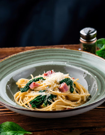 Spaghetti carbonara with spinach and parmesan on wooden tableの素材