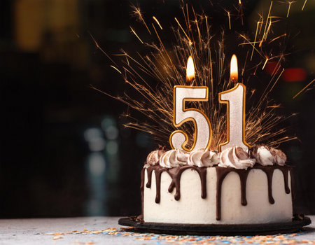 Birthday cake with 55 number candle on dark background with sparklerの素材
