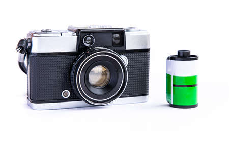 Vintage film camera with 35mm film cartridge isolated on white background.