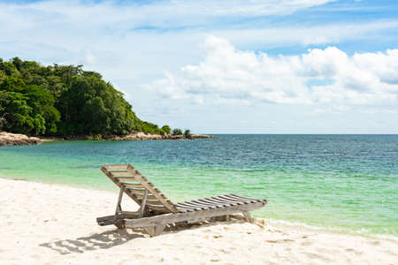 Wooden beach chair on white sand beach in Thailand.