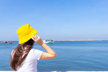 Lonely girl looking at the calm sea with wind in her hair.