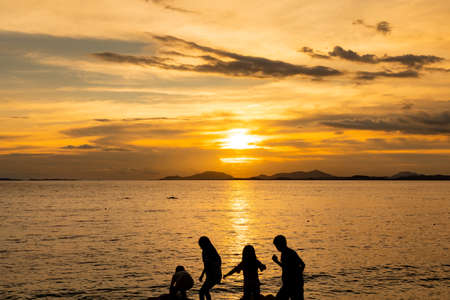 Group of happy kids playing on beach at the sunrise time.の写真素材