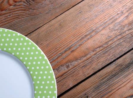 Green dots plate lying on a wooden backgroundの写真素材