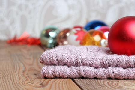Christmas decorations with balls and woolen scarf on a wooden tableの写真素材