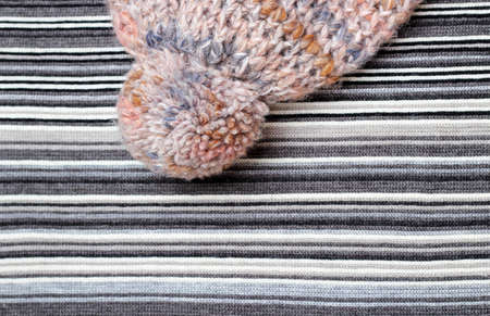 Woolen hat wit pompom on a striped knitting backgroundの写真素材