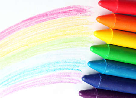 Oil pastel crayons lying on a paper with painted rainbow. Selective focusの写真素材