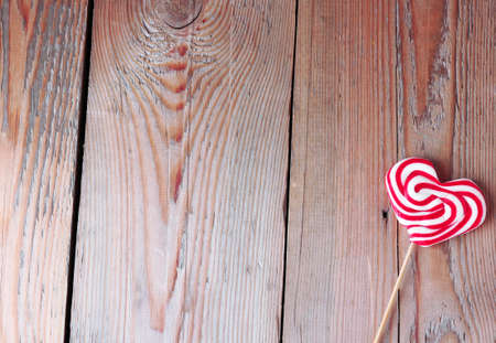 Heart shaped lollipop for Valentine's Day with wooden background. Copy space backgroundの写真素材