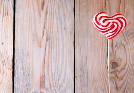Heart shaped lollipop for Valentine's Day with wooden background. Copy space backgroundの写真素材