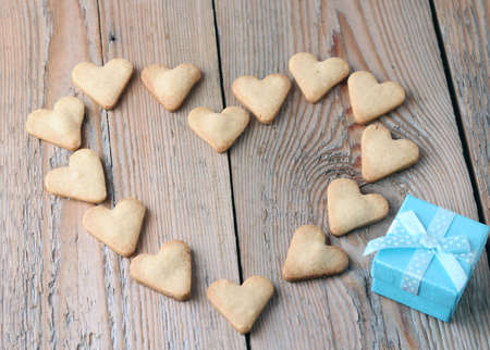 Holidays, love, greetings, food concept. Heart shape cookies with blue gift box on a wooden table for Valentine's day. Vintage style. Copy space background. Selective focusの写真素材
