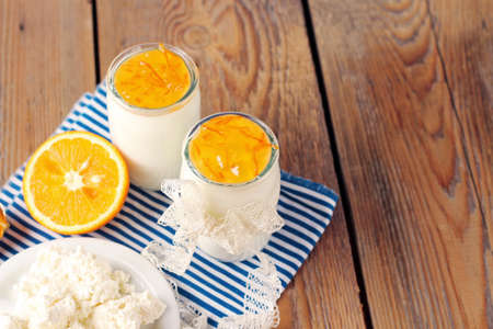 Assortment of breakfast products (homemade yogurt, cottage cheese; orange jam) on a wooden table. Selective focus, copy space backgroundの写真素材