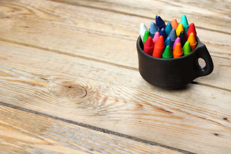 Crayons in a mug on a wooden table. Selective focus, copy space backgroundの写真素材