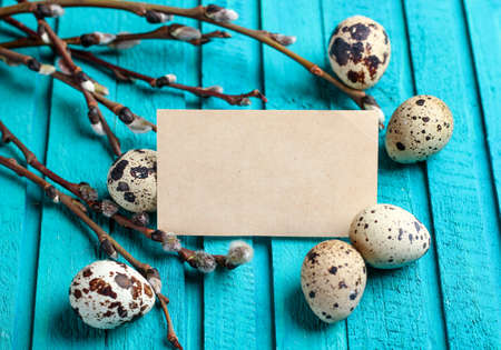 Happy easter concept. Quail eggs and willow branch on a wooden background. Selective focus. Copy  space noteの写真素材