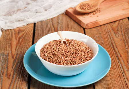 Buckwheat in a bowl with cutting board on a wooden table. Selective focusの写真素材