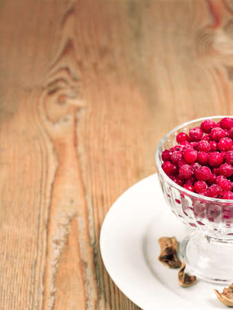 Food and drink, still life concept. Frozen red currant berries in a glass bowl on a wooden table. Selective focus, copy space backgroundの写真素材