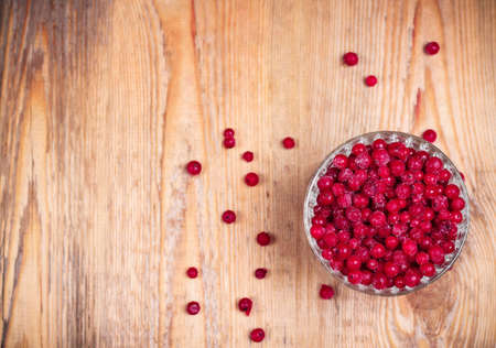 Food and drink, still life concept. Frozen red currant berries in a glass bowl on a wooden table. Selective focus, copy space background, top view, vignetteの写真素材