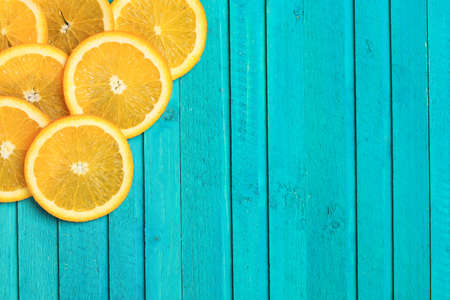 Slices of oranges on a turquoise  wooden background. Selective focus, copy space background, top viewの写真素材