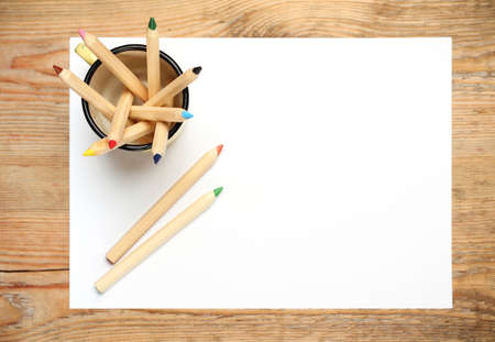 Still life, business, education concept. Pencils in a mug with sheet of paper on a wooden table. Selective focus, copy space background, top viewの写真素材