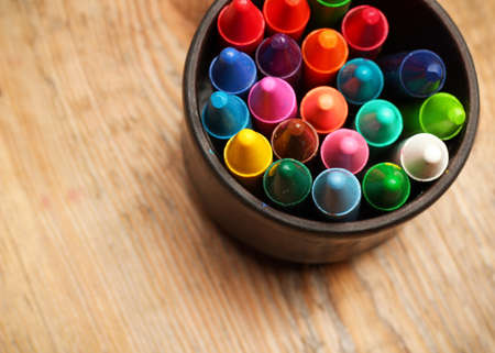 Still life, business, education concept. Crayons in a mug on a wooden table. Selective focus, top viewの写真素材