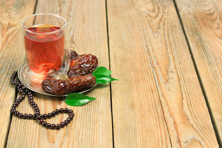 Still life, food and drink, holidays concept. Ramadan dates, tea and beads on a wooden table. Selective focus, copy space backgroundの写真素材
