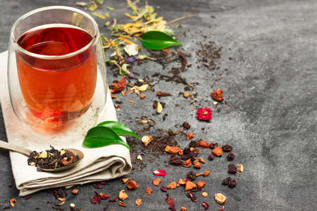 Still life, food and drink concept. Various kinds of tea with a glass of tea on a black chalkboard. Selective focus, copy space background.の写真素材