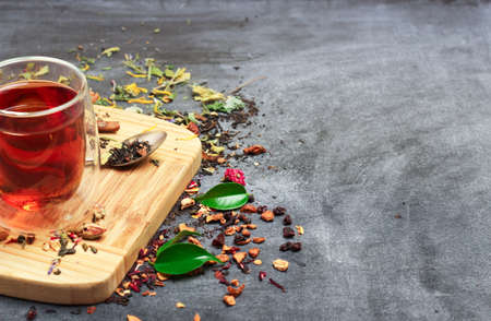 Still life, food and drink concept. Various kinds of tea with a glass of tea on a black chalkboard. Selective focus, copy space background.の写真素材