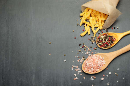 Still life, food and drink concept. Corn cheese puffs with himalayan rose salt and pepper on a black chalkboard. Selective focus, copy space background, top viewの写真素材