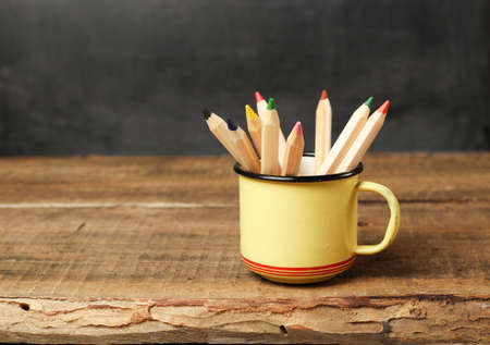 Still life, business, education concept. Pencils in a mug on a wooden table and chalkboard....