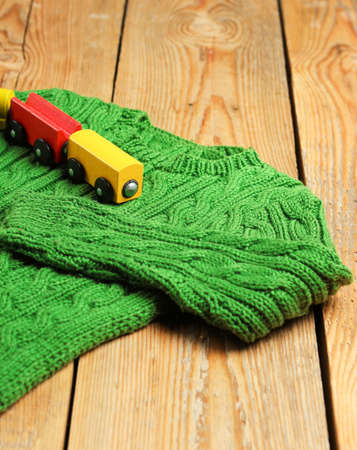 Still life and family concept.Baby boy green sweater with train toy on a wooden table. Selective focusの写真素材