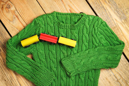 Still life and family concept.Baby boy green sweater with train toy on a wooden table. Selective focus, top viewの写真素材