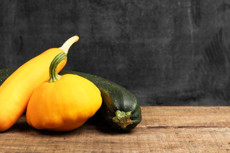 Still life, food and drink, holidays, halloween concept. Pumpkin and zucchini on a wooden table....