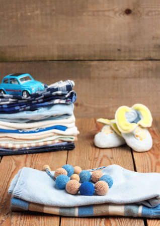 Still life and family concept. Stack of baby boy clothes with toys on a wooden table. Selective focusの写真素材