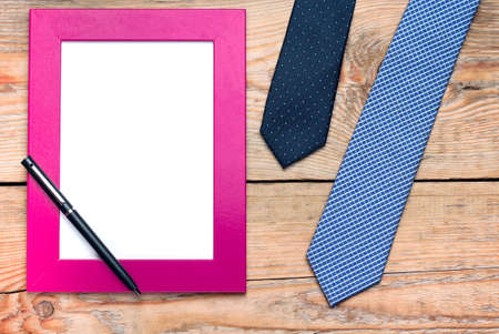 Still life, fashion, business, holidays concept. Tie and frame for father day's greeting on a wooden table. Selective focus, top view, copy space backgroundの写真素材