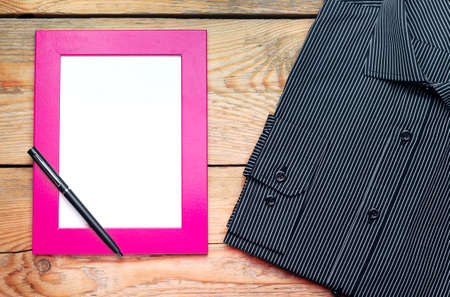 Still life, fashion, business, holidays concept. Shirt and frame for father day's greeting on a wooden table. Selective focus, top view, copy space backgroundの写真素材