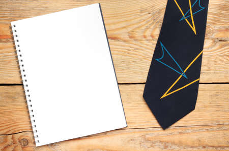 Still life, fashion, business concept. Tie and notepad on a wooden table. Selective focus, top view, copy space backgroundの写真素材
