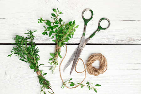 Still life, food and drink, health concept. Mix of fresh herbs on a wooden table, savory, thyme, scissors and rope. Selective focus, top viewの写真素材
